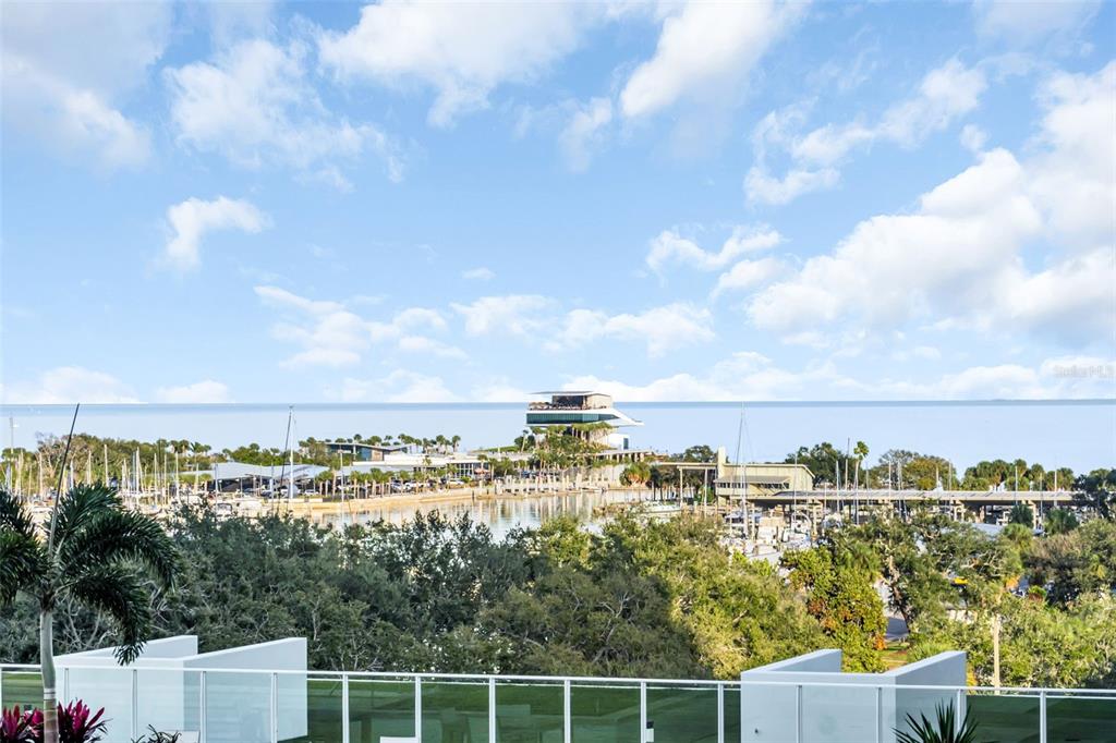 A view from a balcony overlooking a marina, a modern building, and the ocean — 175 1ST STREET S UNIT 702, ST PETERSBURG, FL