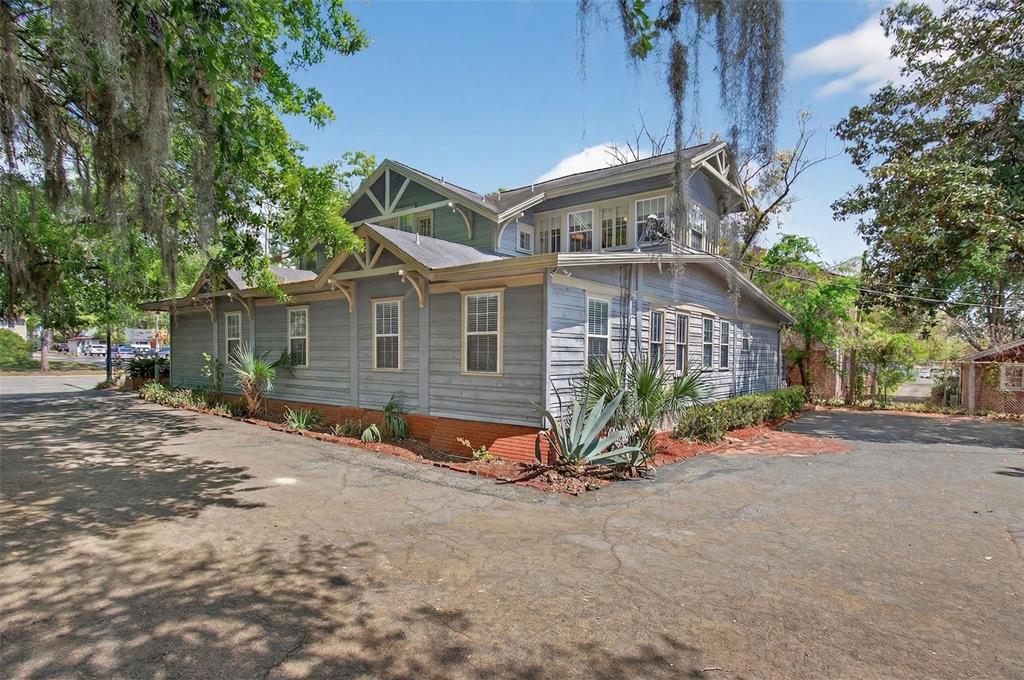 A blue, two-story wood-sided house with a brick foundation stands on an asphalt lot — 1013 SW 2ND AVENUE, GAINESVILLE, FL