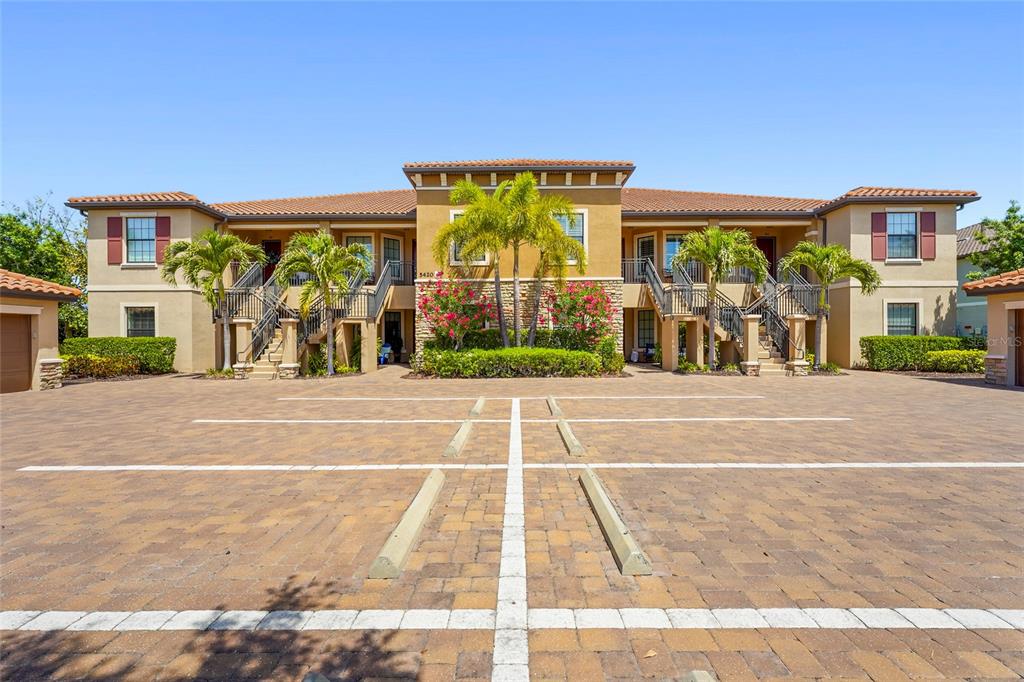 A two-story apartment building with a paved parking lot in the foreground — 5420 CICERNONE STREET UNIT 203, SARASOTA, FL