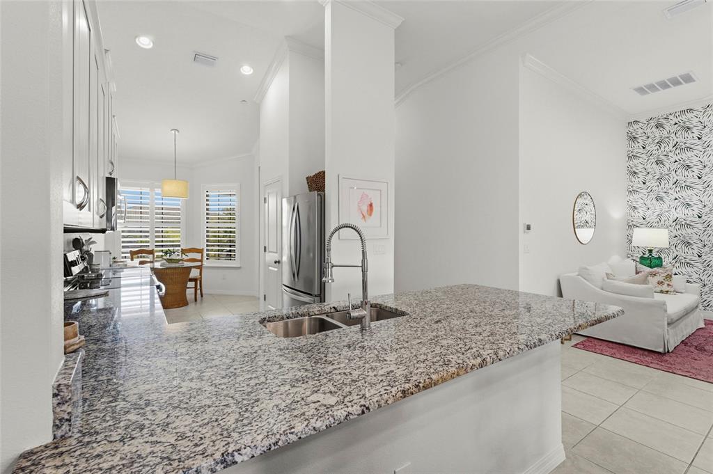 A kitchen with granite countertops and a sink overlooks a dining area and living room — 5420 CICERNONE STREET UNIT 203, SARASOTA, FL