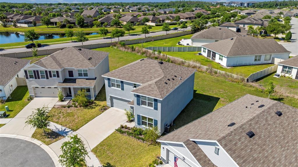 An aerial view shows several suburban houses with driveways and lawns near a small lake — 16673 WINDMILL FORGE PASS, WIMAUMA, FL