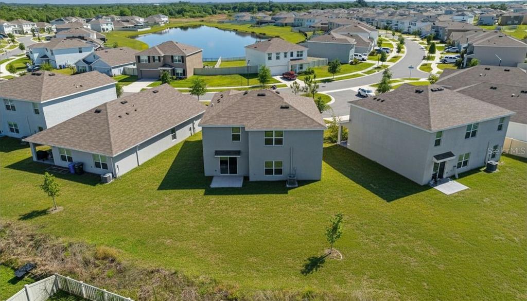 An aerial view shows the backyards of several suburban houses near a small pond — 16673 WINDMILL FORGE PASS, WIMAUMA, FL