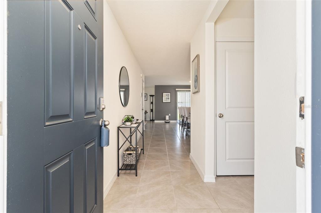 A view from an open front door into a tiled entryway leading toward a dining area — 16673 WINDMILL FORGE PASS, WIMAUMA, FL