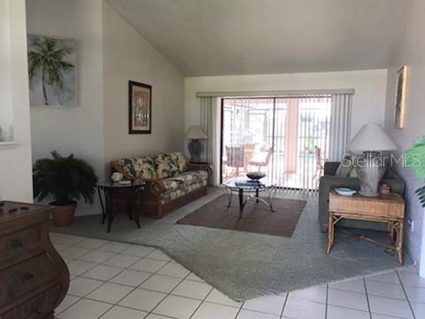 A living room with a floral sofa, a glass coffee table, and a sliding glass door — 7160 CARLSBAD TERRACE, ENGLEWOOD, FL