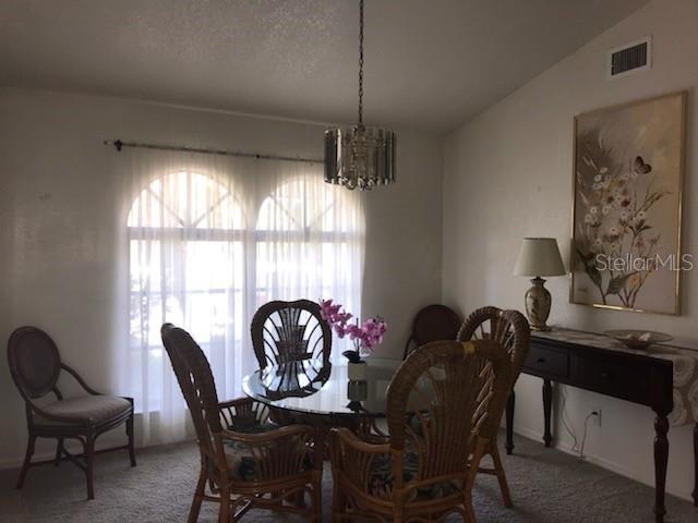 A dining room features a glass table with wicker chairs, a chandelier, and arched windows — 7160 CARLSBAD TERRACE, ENGLEWOOD, FL