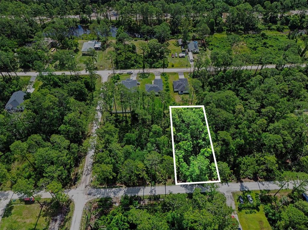 An aerial view shows a rectangular, tree-covered vacant lot outlined in white along a road — 1465 EAST PARKWAY, DELAND, FL