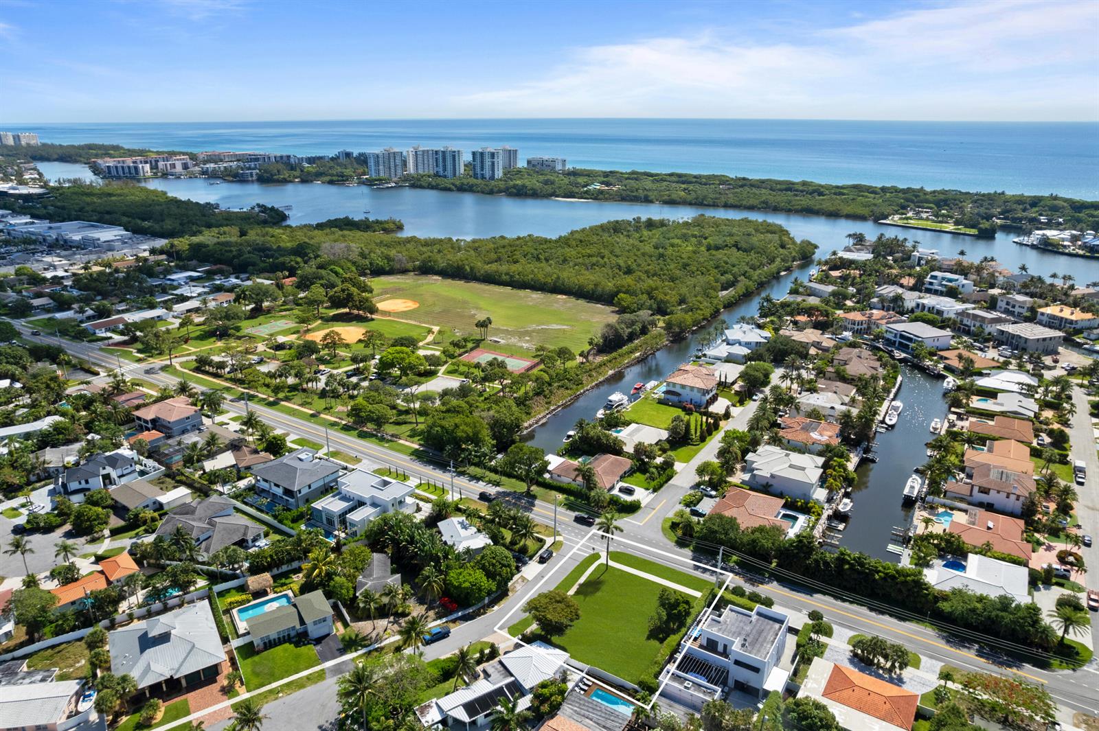 An aerial view shows a residential neighborhood with a canal, park, and distant ocean — 498 NE 14th Street, Boca Raton FL 33432, BOCA RATON, FL