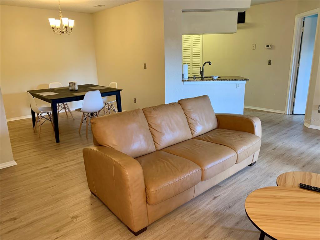 A living room with a tan leather sofa, dining area, and open kitchen counter — 2550 N ALAFAYA TRAIL UNIT 12203, ORLANDO, FL