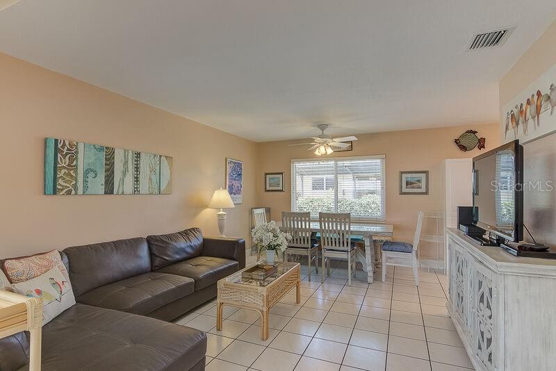 A living and dining area features a brown sectional sofa, tiled floors, and a television — 6020 MIDNIGHT PASS ROAD UNIT 1, SARASOTA, FL
