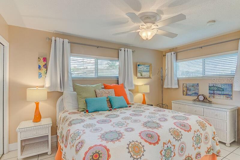 A bedroom features a bed with a patterned quilt, two windows, and white wicker furniture — 6020 MIDNIGHT PASS ROAD UNIT 1, SARASOTA, FL