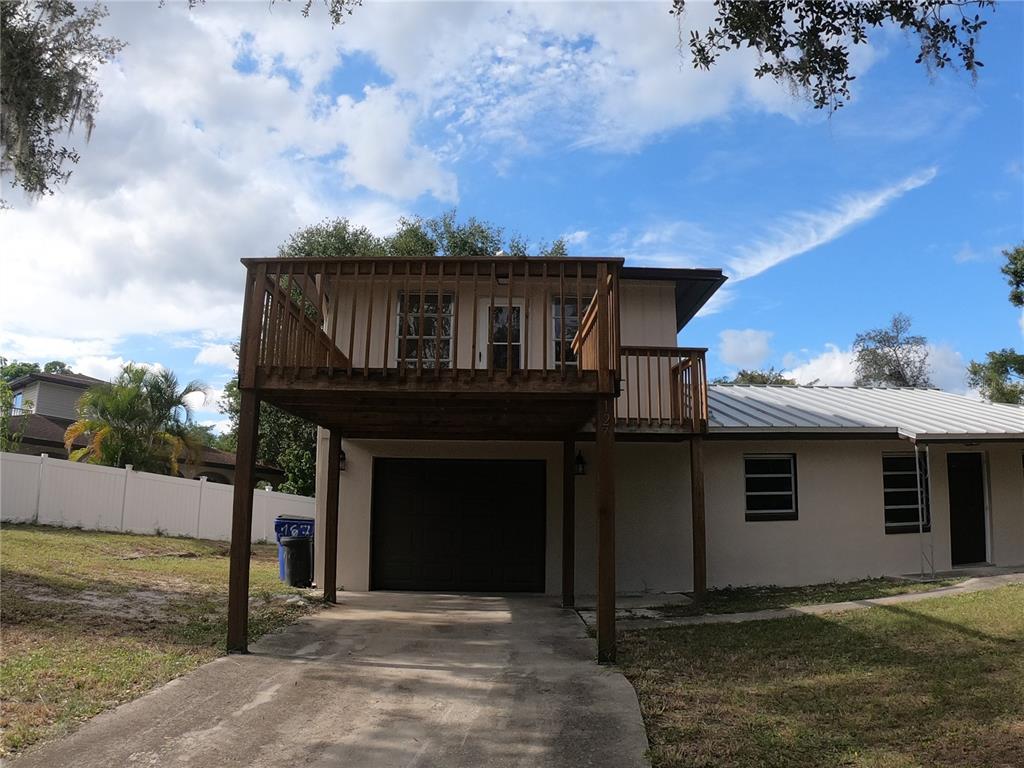 A two-story house features a large wooden deck built over a single-car garage — 127 JAMISON AVENUE, LAKE PLACID, FL