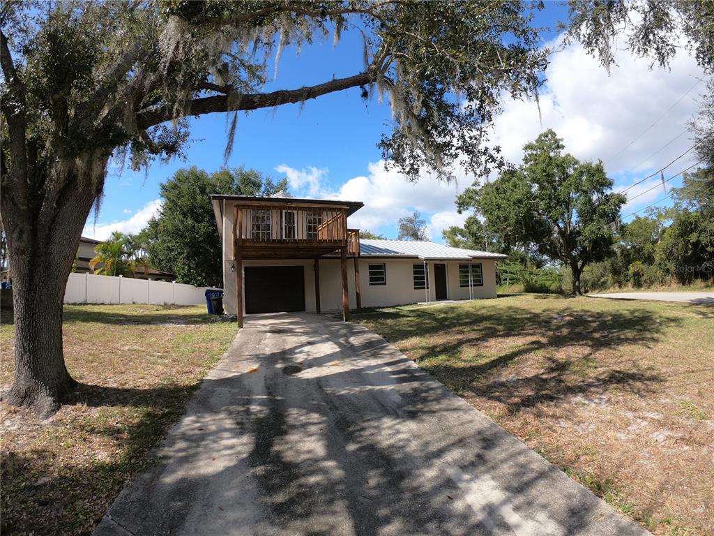 A two-story house with a wooden balcony above a garage and a concrete driveway — 127 JAMISON AVENUE, LAKE PLACID, FL