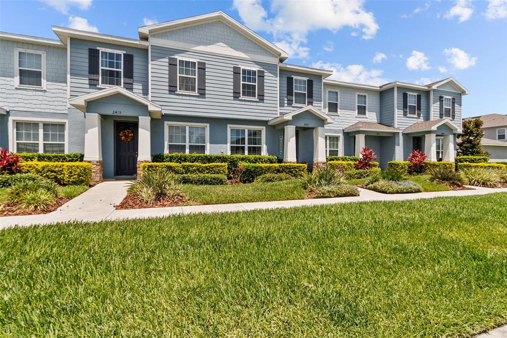 A multi-unit residential building with blue siding, white trim, and a landscaped front lawn — 2421 HEARTH DRIVE, ODESSA, FL