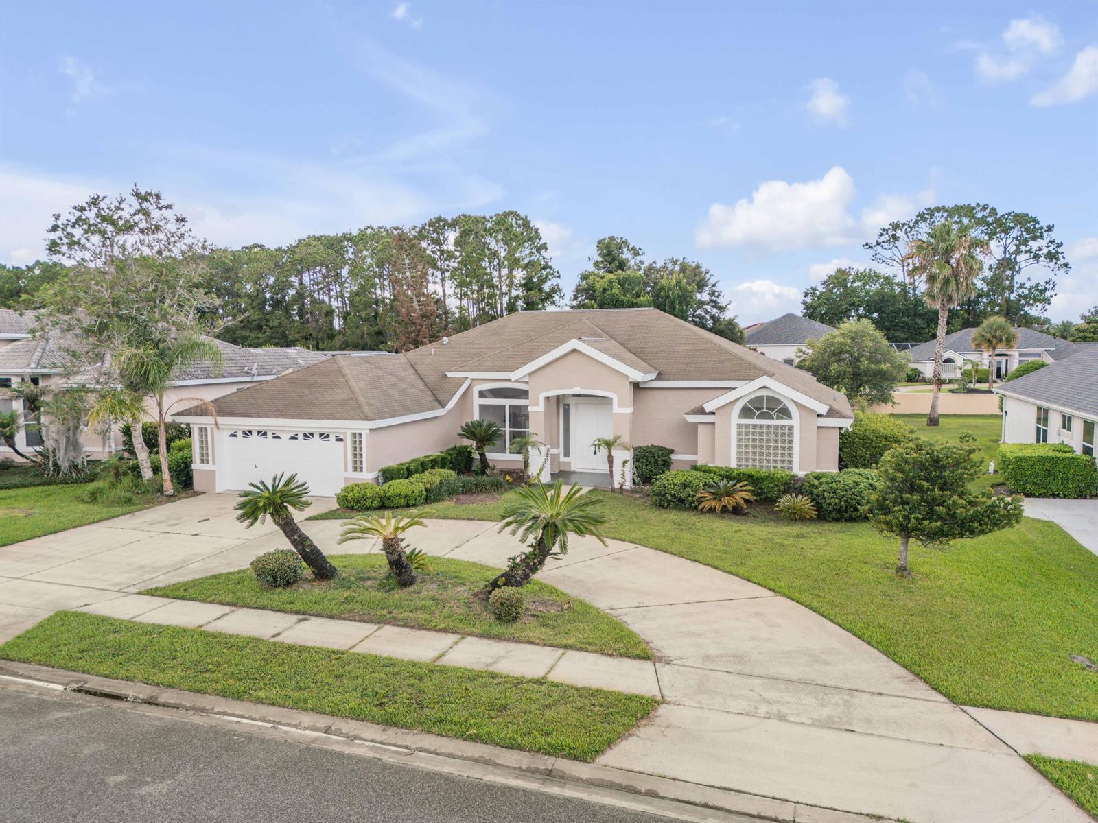 A single-story beige house with a curved driveway, palm trees, and a two-car garage — 2911 Cypress Ridge Trail, Port Orange FL 32128, PORT ORANGE, FL