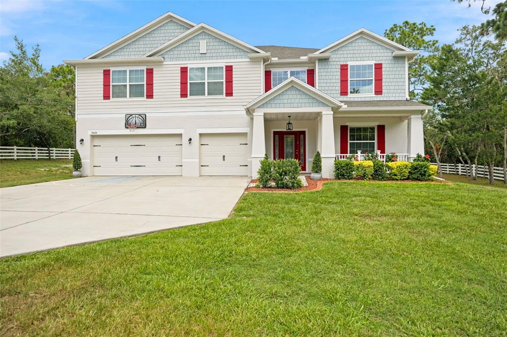 A two-story house with a two-car garage, light siding, and red window shutters — 9025 MAZETTE ROAD, WEEKI WACHEE, FL
