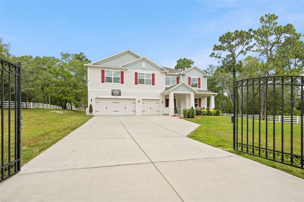 A two-story suburban house with a three-car garage and a gated concrete driveway — 9025 MAZETTE ROAD, WEEKI WACHEE, FL