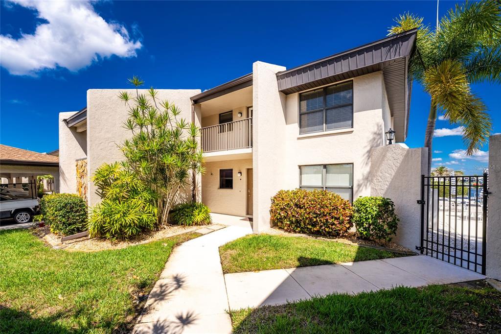 A two-story stucco townhouse features a balcony, a concrete walkway, and a metal gate — 3670 BAL HARBOR BOULEVARD UNIT 1F, PUNTA GORDA, FL