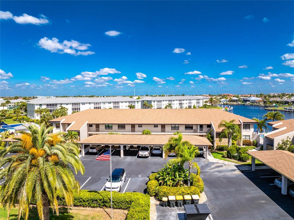 An aerial view shows a multi-story apartment building with a covered parking area and landscaping — 3670 BAL HARBOR BOULEVARD UNIT 1F, PUNTA GORDA, FL