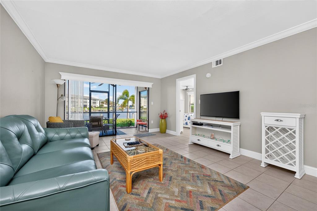 A living room features a teal leather sofa, a patterned rug, and a water view — 3670 BAL HARBOR BOULEVARD UNIT 1F, PUNTA GORDA, FL