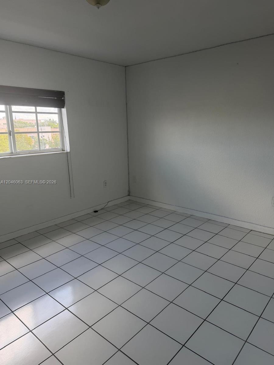 An empty room features white walls, white tiled flooring, and a single window — 21 E 3rd St # 405, Hialeah FL 33010, HIALEAH, FL