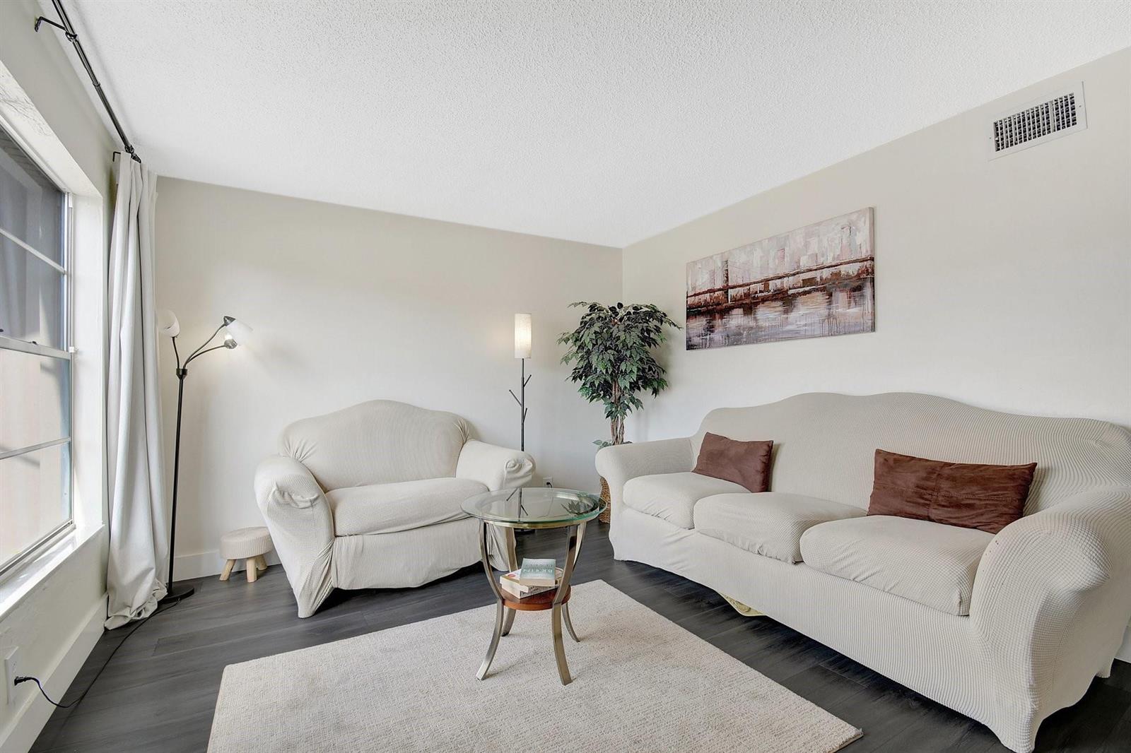 A living room with light-colored sofas, a glass-topped side table, and dark wood-look flooring — 3708 SW 59th Terrace # 68, Davie FL 33314, DAVIE, FL