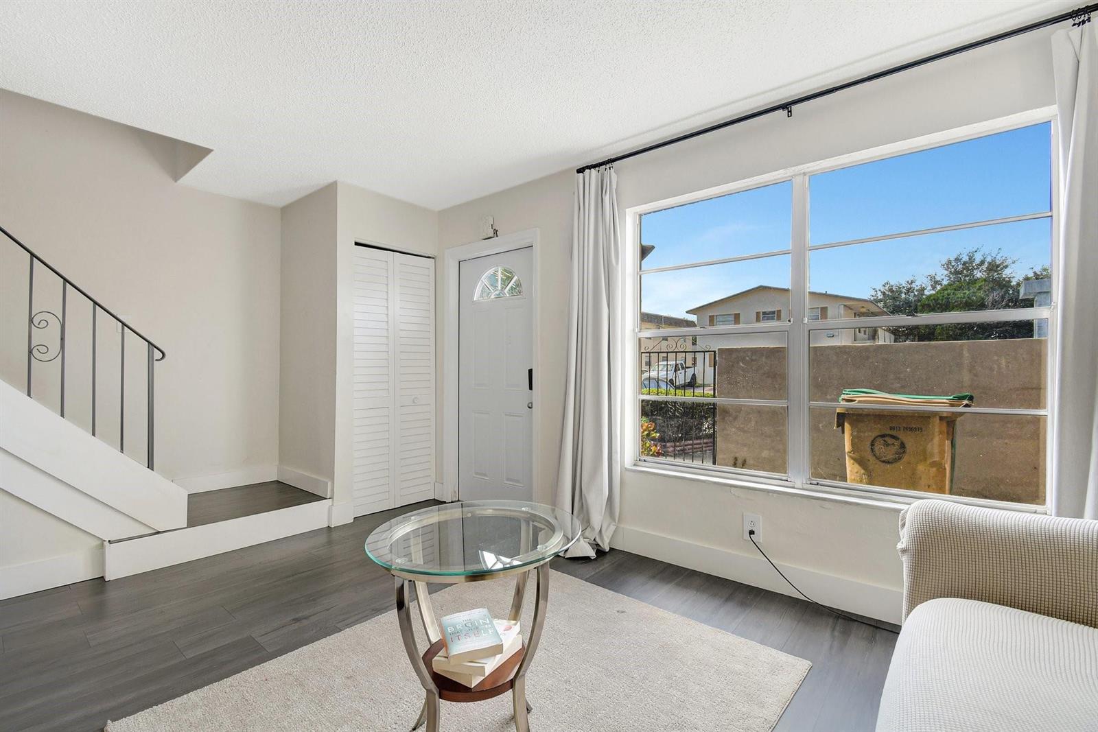 A living room features dark wood-look flooring, a glass coffee table, stairs, and a large window — 3708 SW 59th Terrace # 68, Davie FL 33314, DAVIE, FL