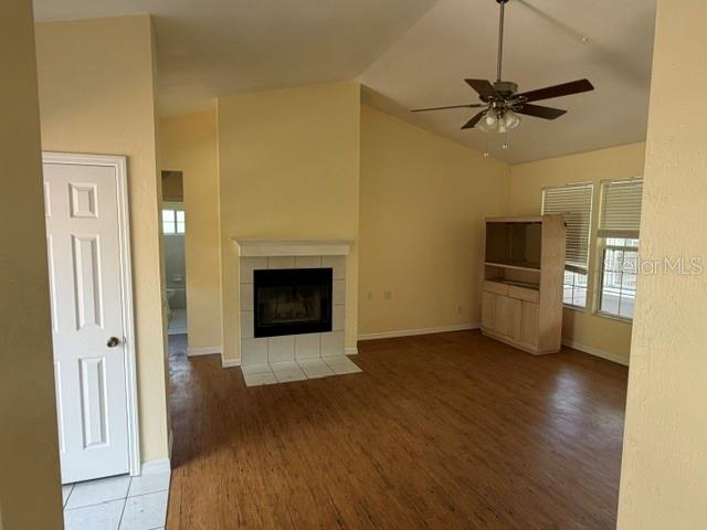 A living room features a fireplace, wood-look flooring, a ceiling fan, and a white door — 2144 NW 85TH TERRACE, GAINESVILLE, FL