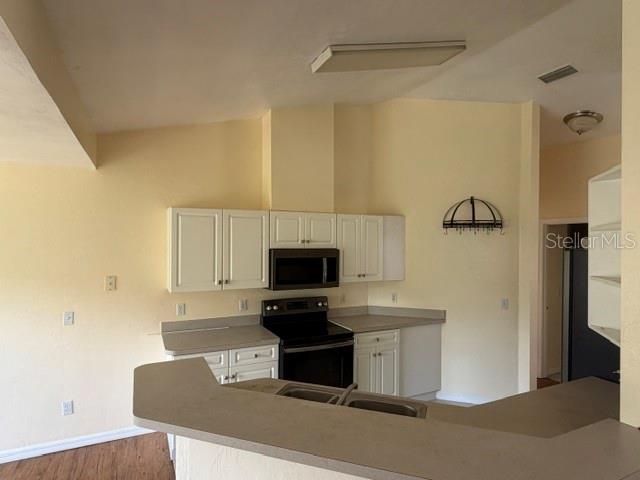 A kitchen features white cabinets, a black stove, and a peninsula counter — 2144 NW 85TH TERRACE, GAINESVILLE, FL