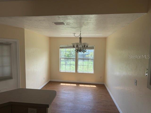 A dining area features light-colored walls, a chandelier, a window, and wood-look flooring — 2144 NW 85TH TERRACE, GAINESVILLE, FL