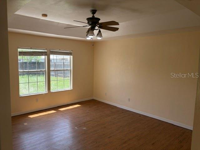 An empty room features light-colored walls, wood-look flooring, a ceiling fan, and two windows — 2144 NW 85TH TERRACE, GAINESVILLE, FL