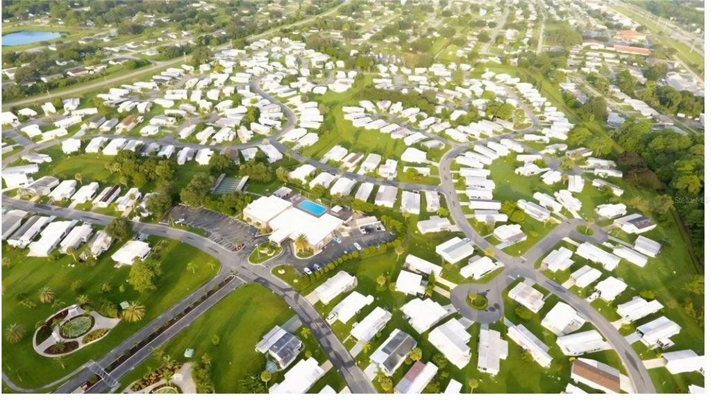 An aerial view of a residential mobile home community featuring a central clubhouse and pool — 6789 HAKI COURT, NORTH PORT, FL