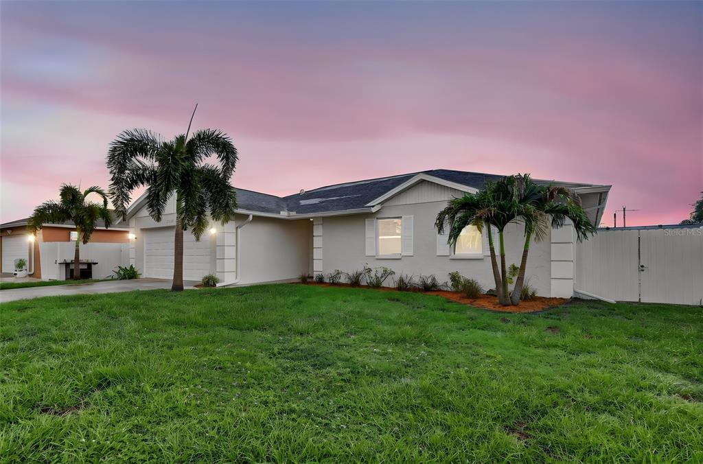 A single-story house with a white exterior, two palm trees, and a grassy front yard — 4063 PALAU DRIVE, SARASOTA, FL