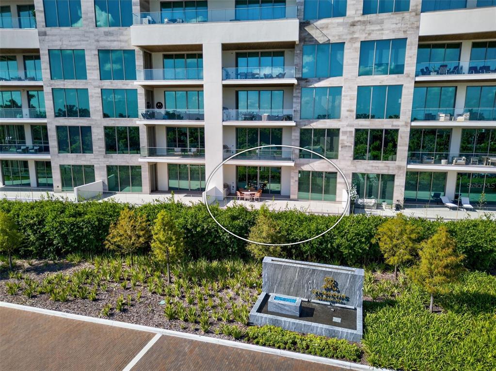 An exterior view of a multi-story apartment building featuring a ground-floor patio with outdoor furniture — 1591 GULF OF MEXICO DRIVE UNIT 216, LONGBOAT KEY, FL