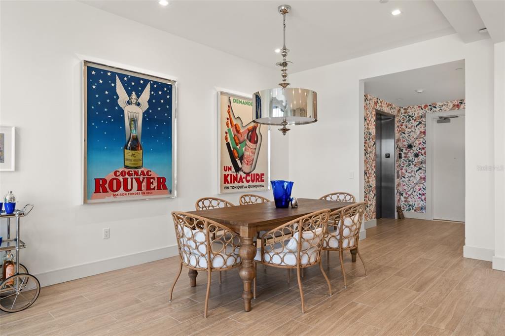 A dining room features a wooden table, rattan chairs, vintage posters, and a drum chandelier — 1591 GULF OF MEXICO DRIVE UNIT 216, LONGBOAT KEY, FL