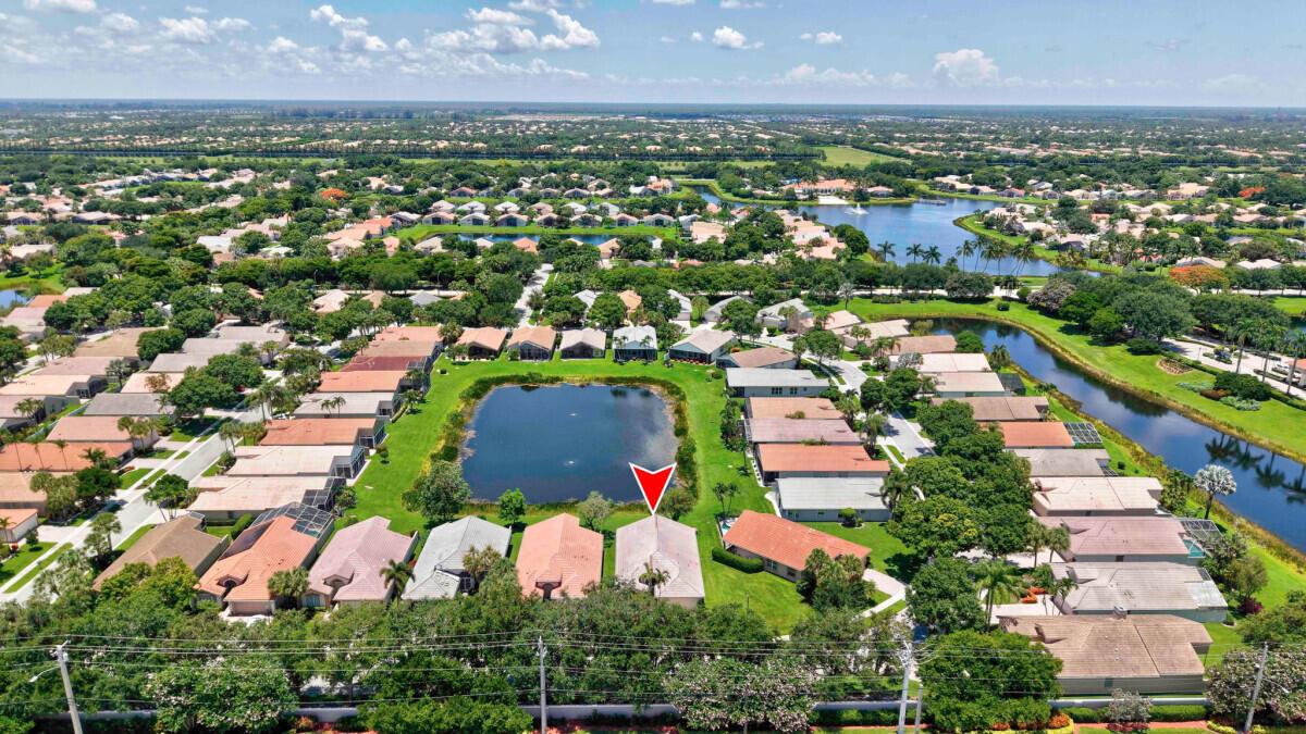 An aerial view of a residential neighborhood featuring houses surrounding a central pond — 11709 Castellon Court, Boynton Beach FL 33437, BOYNTON BEACH, FL