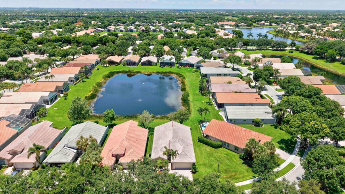 An aerial view of a residential neighborhood featuring houses surrounding a central pond — 11709 Castellon Court, Boynton Beach FL 33437, BOYNTON BEACH, FL