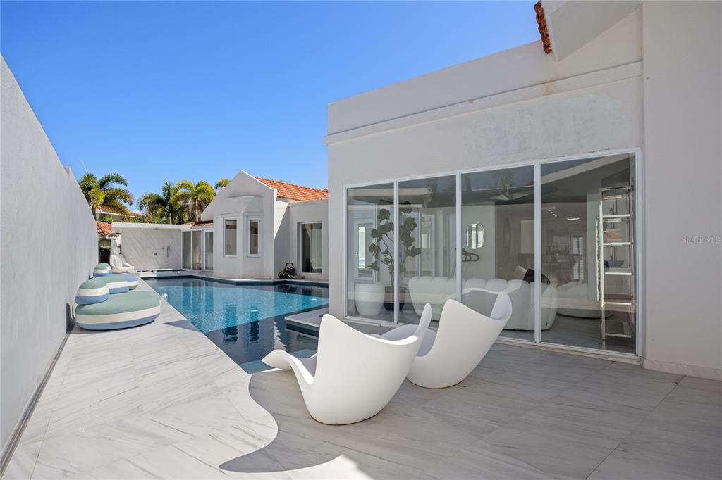 A modern white house features a swimming pool, patio seating, and large glass sliding doors — 394 DORADO BEACH EAST, DORADO, PR