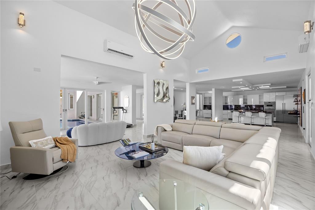 A spacious open-concept living room features white marble floors, a large sectional, and vaulted ceilings — 394 DORADO BEACH EAST, DORADO, PR