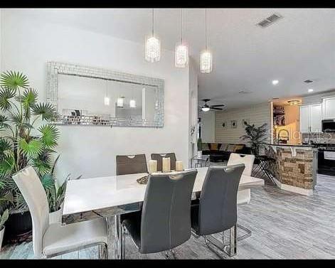 A dining area features a white table, gray chairs, pendant lights, and a large wall mirror — 911 LA TERRAZA LANE, KISSIMMEE, FL