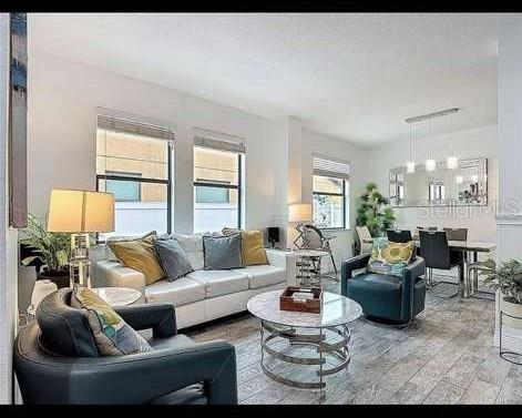 A living room with a white sofa, dark armchairs, a glass coffee table, and large windows — 911 LA TERRAZA LANE, KISSIMMEE, FL