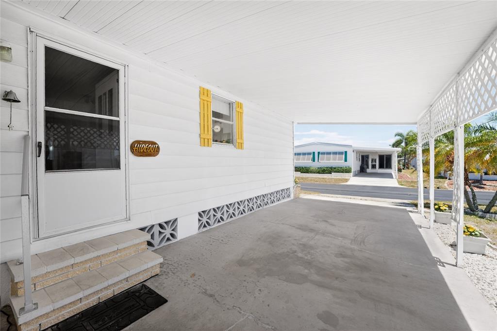 A covered concrete carport features white siding, a front door with steps, and yellow shutters — 17 N FLORA VISTA STREET, ENGLEWOOD, FL