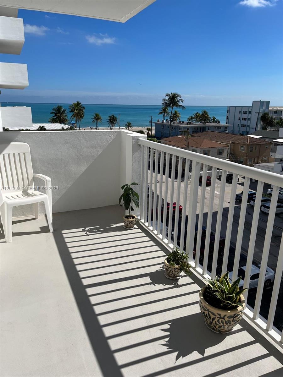 A balcony with a white railing overlooks the ocean and a street with parked cars — 1601 S Ocean Dr # 605, Hollywood FL 33019, HOLLYWOOD, FL
