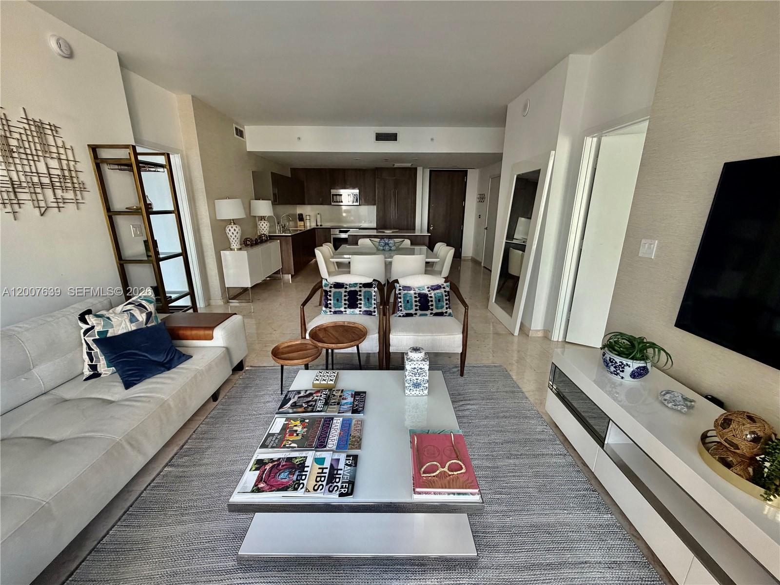 A modern living room and dining area feature white furniture, a grey rug, and kitchen — 88 SW 7th St # 1109, Miami FL 33130, MIAMI, FL