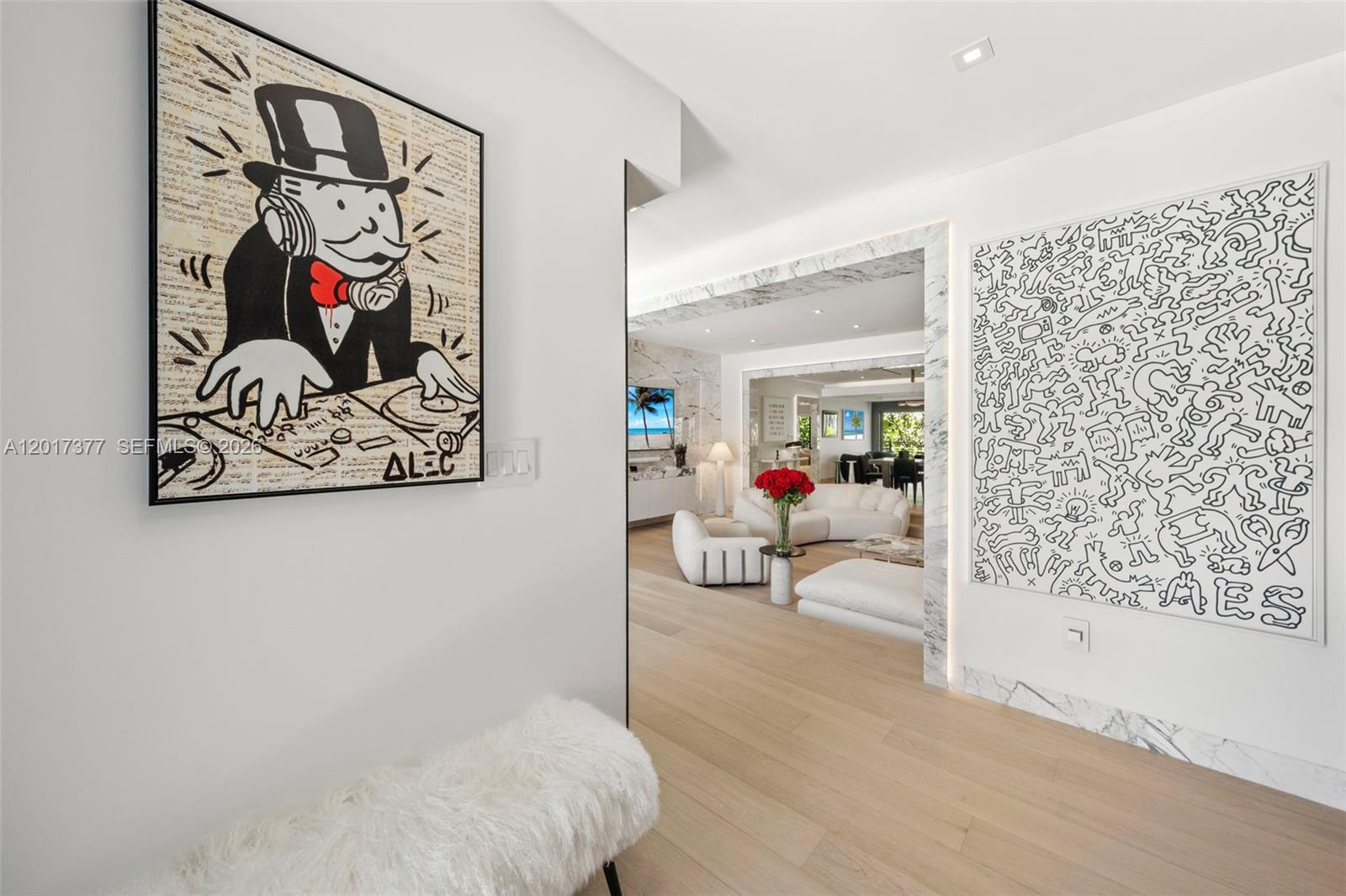 A hallway with two large framed artworks leads into a bright, modern living room — 5750 La Gorce Dr, Miami Beach FL 33140, MIAMI BEACH, FL