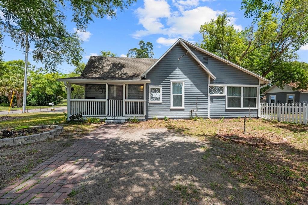 A blue-sided house with a front porch, brick walkway, and white picket fence — 5416 8TH STREET, ZEPHYRHILLS, FL