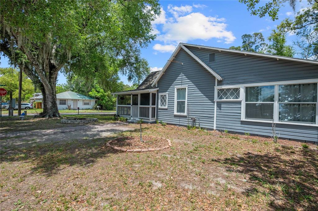 A gray-sided house with a screened-in porch stands on a lot with large trees — 5416 8TH STREET, ZEPHYRHILLS, FL