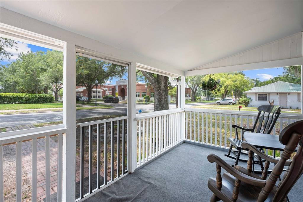 A screened-in porch features gray carpeting, white railings, and two wooden rocking chairs — 5416 8TH STREET, ZEPHYRHILLS, FL