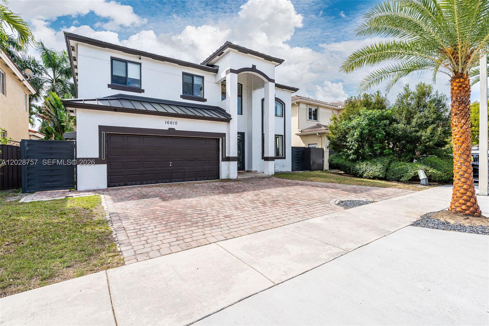 A two-story white house with a dark brown garage door and a brick-paved driveway — 16610 SW 57th Ln, Miami FL 33193, MIAMI, FL