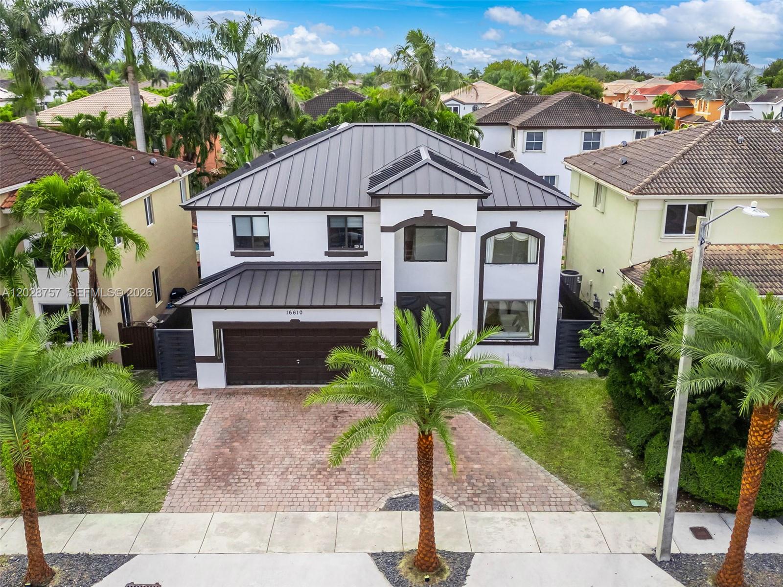 An aerial view shows a two-story house with a dark metal roof and driveway — 16610 SW 57th Ln, Miami FL 33193, MIAMI, FL