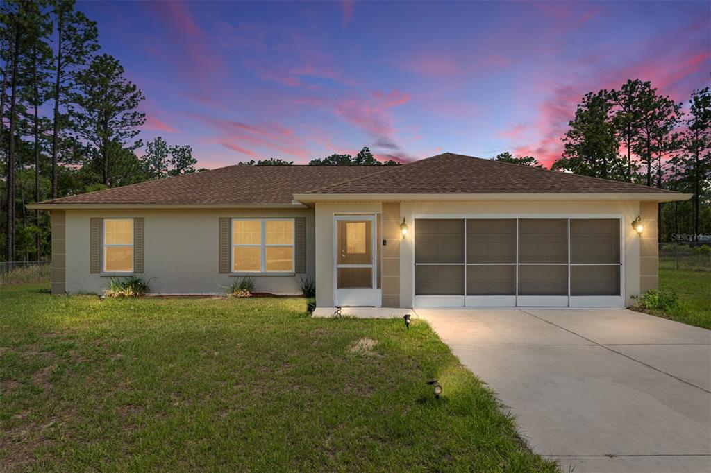 A single-story house with a screened garage and front door sits on a grassy lot — 13130 SW 76TH LANE, DUNNELLON, FL